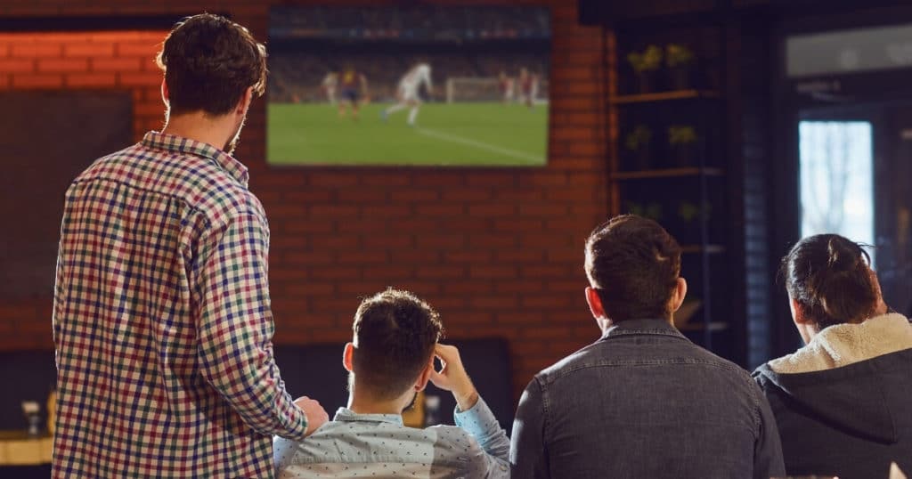 sports fans watching football in the pub